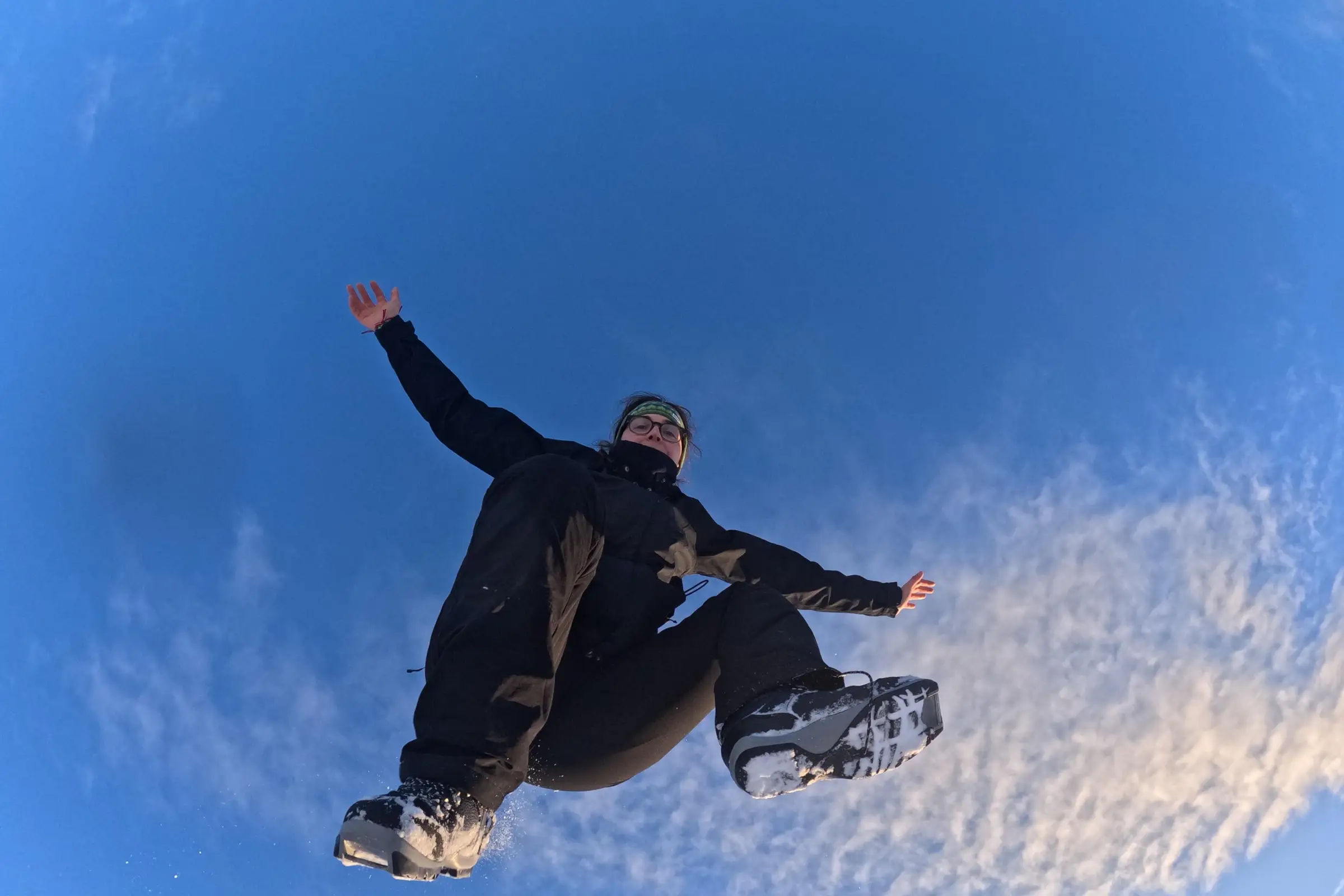Asia mid-jump against a deep blue winter sky, photographed from below