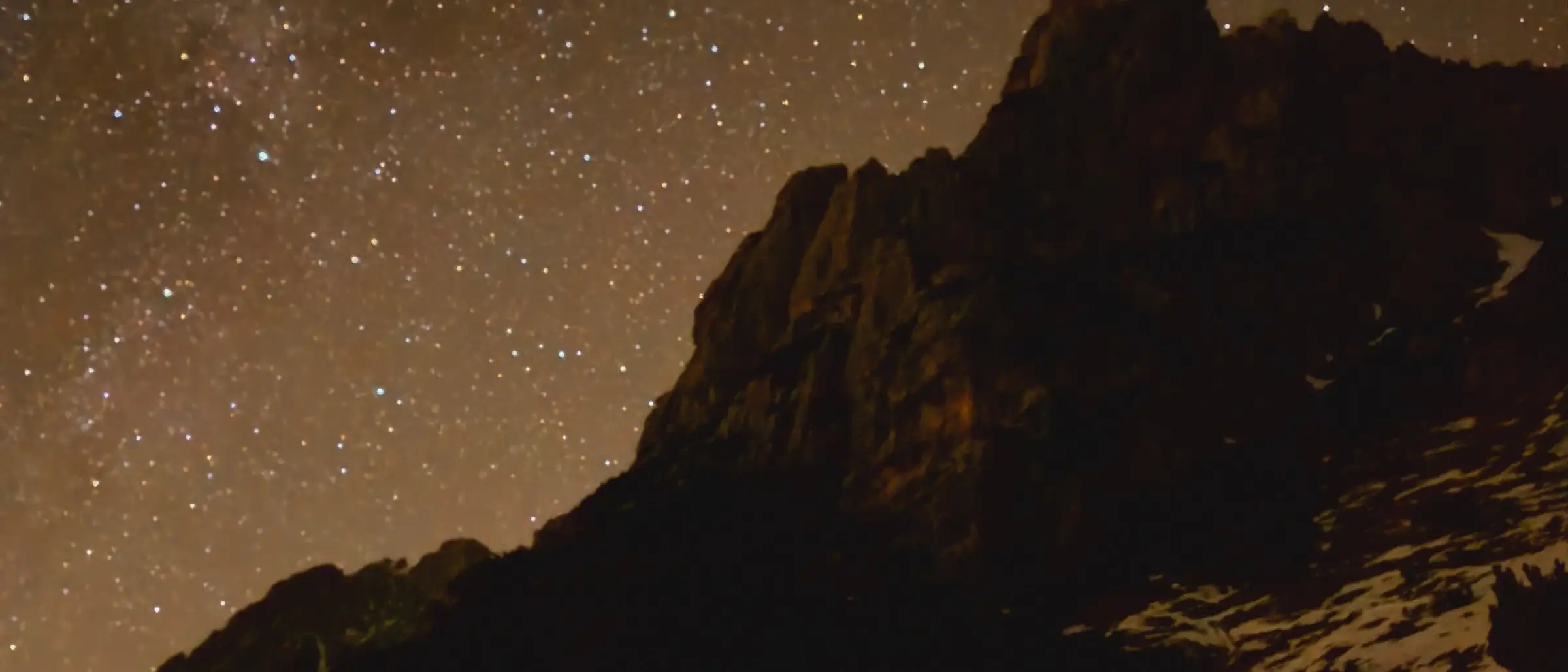 The Milky Way over a dark ridge, snow in the foreground